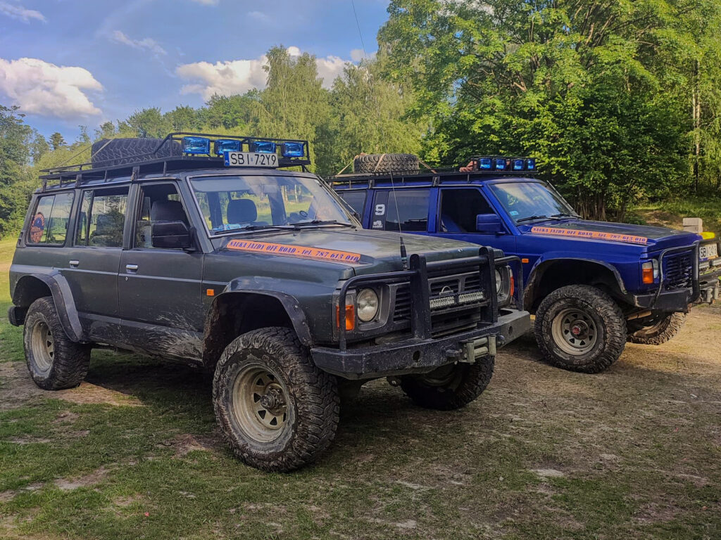 Dwa pojazdy terenowe z oznaczeniami na dachu, stojące obok siebie na zewnątrz.