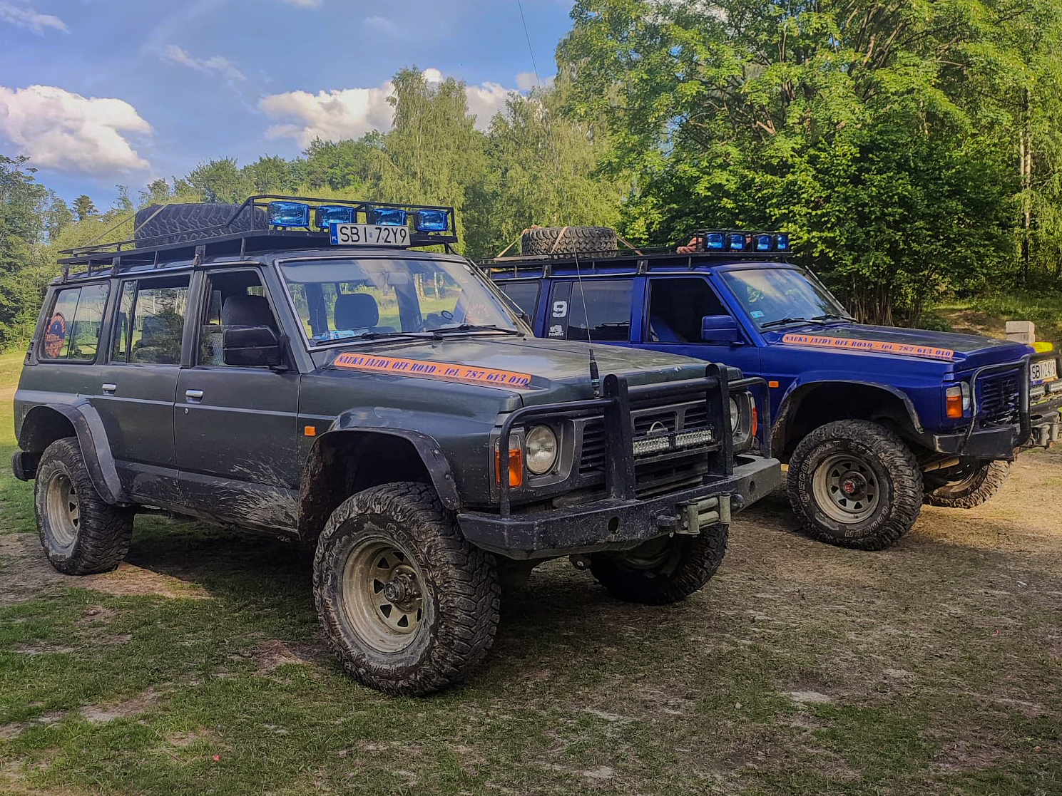 Dwa pojazdy terenowe z oznaczeniami na dachu, stojące obok siebie na zewnątrz.